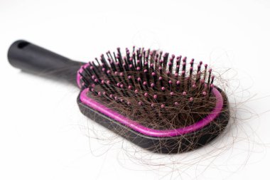 Beyaz arka planda düşmüş saçları olan bir tarak. Saç dökülmesi, saç fırçası..