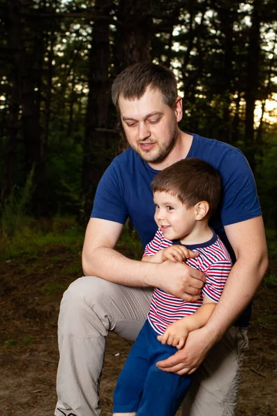 Dad and son walk in the coniferous pine forest in the evening. Father\'s Day, the role of dad in the child\'s life, family