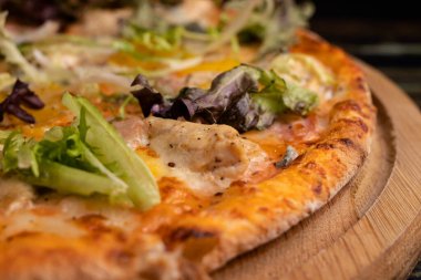 Tahta arka planda etli, peynirli, biberli ve otlu pizza. İtalyan ulusal mutfağı, restoranda lezzetli hamur işleri.