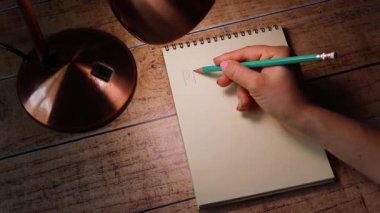 Kız bir defter kağıdına mükemmel olmayan bir kalemle yazıyor. Aşk ifadeleri, iş ve yaşam hedefleri motive edici.