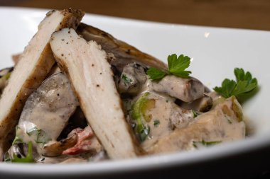 Beyaz tabakta et dilimlenmiş sıcak salata. Restoran yemekleri. Et salatası, vejetaryen değil, tavuk.