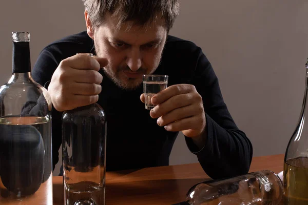 Человек в алкогольном опьянении держит стакан алкоголя. Алкоголизм, зависимость, бред — стоковое фото