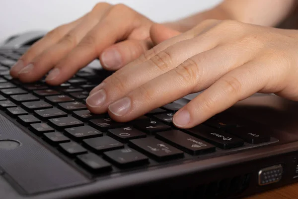 人类的手在黑色的笔记本电脑键盘上打字 图库图片