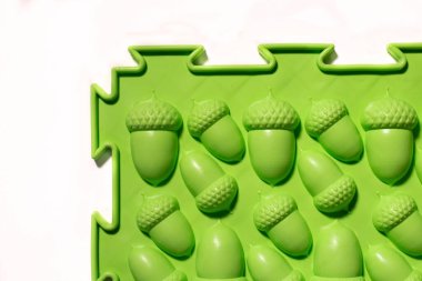 Beyaz arkaplanda meşe palamudu şeklinde yeşil ortopedi minderi. Çocuklarda düz taban ve ayak masajı önleme