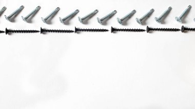 Beyaz arka plan pankartıyla kendini kesen yazılar. İnşaat aletleri, bağlanmak için kendi kendine dokunan vidalar. Siyah vida donanımı