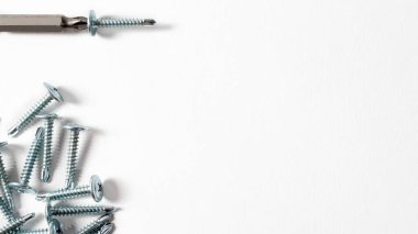 Beyaz bir arkaplandaki özkesiciler ve tornavida. Mesaj için yer var. İplikle vidalayın - inşaat için bağlayıcılar, tamir için araçlar ve aksesuarlar