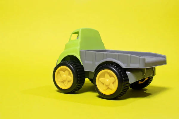 Autocarro giocattolo su sfondo giallo - attrezzature per l'edilizia per bambini. Giocattoli di plastica per bambini luminosi, infanzia del camion della discarica. — Foto Stock