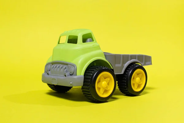 Autocarro giocattolo su sfondo giallo - attrezzature per l'edilizia per bambini. Giocattoli di plastica per bambini luminosi, infanzia del camion della discarica. — Foto Stock