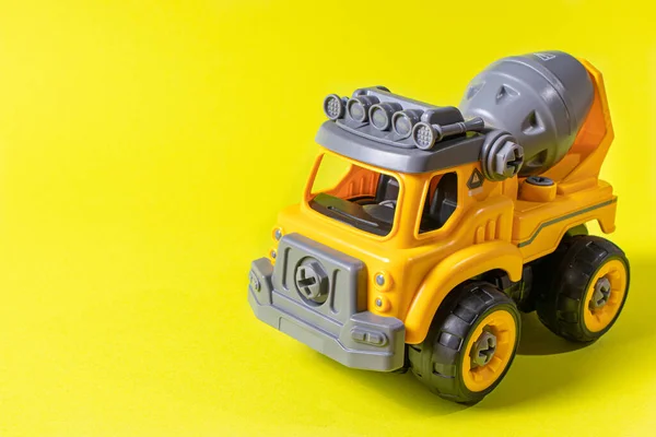 Pomarańczowy betoniarka zabawki maszyna do pisania na żółtym tle. Baner z miejscem na tekst dla sklepu z zabawkami. Przestrzeń chroniona. — Zdjęcie stockowe