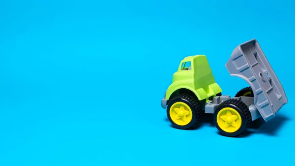 Autocarro giocattolo su sfondo blu - attrezzature per l'edilizia per bambini. Giocattoli di plastica per bambini luminosi, infanzia del camion della discarica. Copyspace banner posto per il testo. — Foto Stock