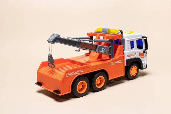 Toy carro attrezzi arancione su sfondo beige. Auto per bambini per il carico e il trasporto di auto. — Foto Stock