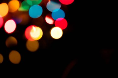 Siyah üzerine parlak bir arka plan. Yeni yıl ve diğer tatiller için ışıltılı ışıklar yanar.