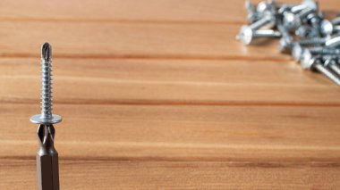 Kahverengi ahşap arka planda bir tornavida ve kendini kesen. Evi onarmak için araç gereç inşa ediliyor