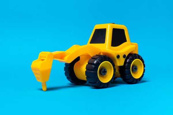 儿童玩具黄色牵引车在蓝色底座上操练 塑料建筑设备 玩具店 — 图库照片