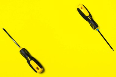 Sarı arka planda iki siyah ve sarı tornavida ve metin için boşluk. Araç gereç, inşaat ve atölye, ev onarımı, içecek işi