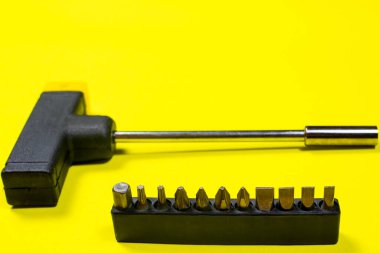 Bir tornavida nozülü set ve bir tornavida sarı arka planda, kopyalanmış uzay metni için boşluk. İnşaat ve onarım malzemeleri.