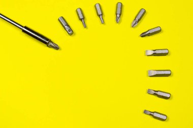 Bir tornavida nozülü set ve bir tornavida sarı arka planda, kopyalanmış uzay metni için boşluk. İnşaat ve onarım malzemeleri.