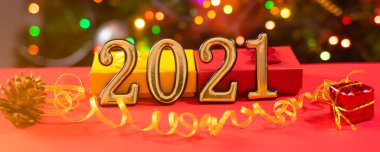 İçinde 2021 haneli güzel bir noel kartı ve arkasında kırmızı bir arka planda altın bir kurdele var. Yeni yıl, şenlik havası, boğa yılı.