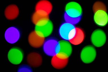 Siyah üzerine parlak bir arka plan. Yeni yıl ve diğer tatiller için ışıltılı ışıklar yanar..