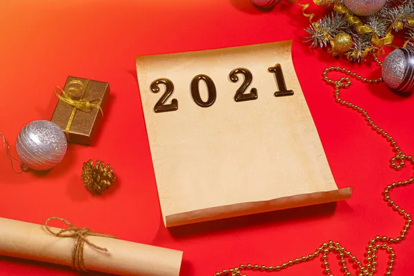 Papel pergamino y un pergamino para la lista de tareas pendientes y texto para el nuevo año 2021 sobre un fondo rojo. Navidad, tarjeta de vacaciones con planes para el próximo año — Foto de Stock