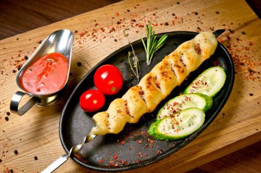 Taze salatalık, domates ve barbekü soslu ızgara tavuk kebabı. Tahta tepside