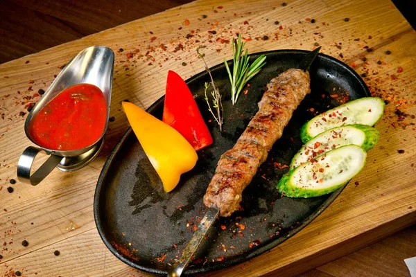 Taze salatalıklı ızgara biftek kebabı, tatlı biber ve barbekü sosu. Tahta tepside