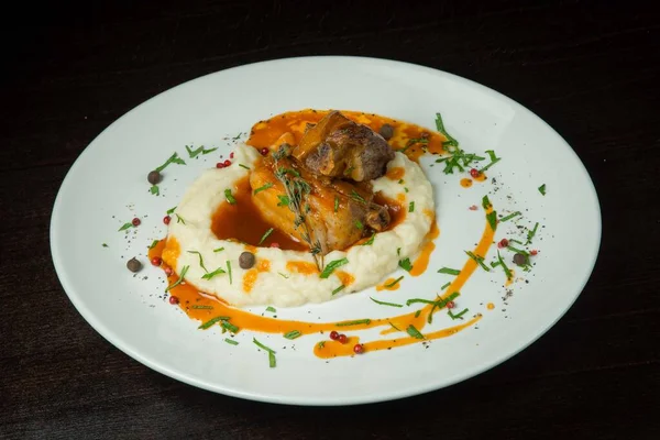Patates püresiyle ördek bacağı. Beyaz bir tabakta. Siyah arkaplanda