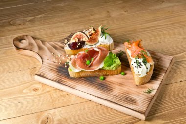 Somon, jamon ve incirle servis edilir. Tahta üzerinde. Kırsal ahşap bir arka planda