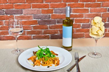 Karides ve roka ile makarna. Beyaz bir tabakta. Bir bardak suyla.