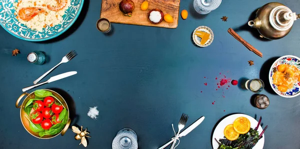 Karidesli risotto 'nun en üst görüntüsü. Domates salatası. Doğu çaydanlığı. Çerçevenin ortası boş. Siyah masa
