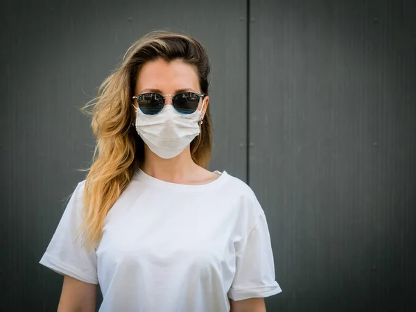 Tıbbi koruyucu maske takan bir kız. Gri bir arkaplanda. Koronavirüs salgını sırasında