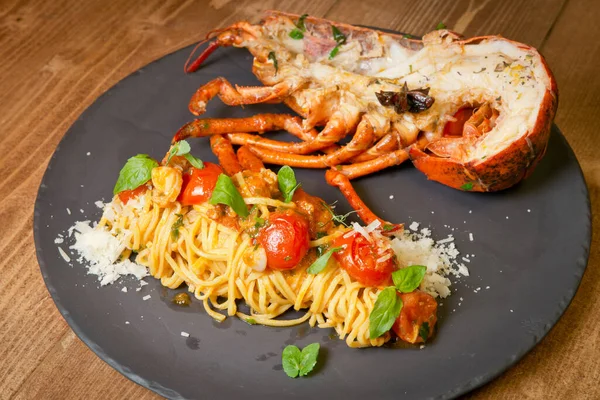 Istakoz ve domates turşulu spagetti. Siyah bir tabakta. Kırsal bir ahşap kırsalda