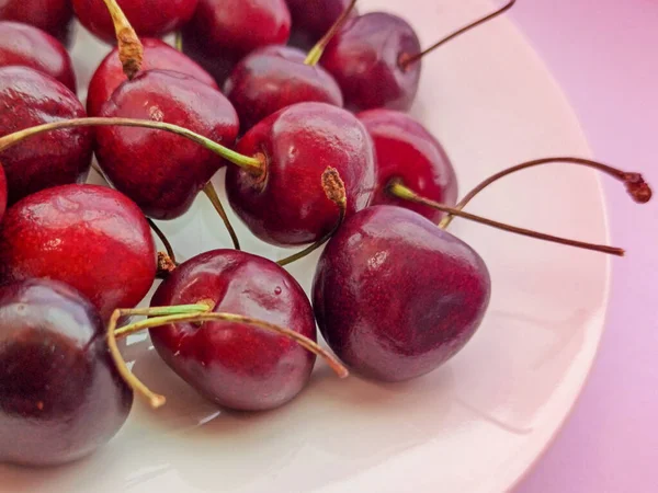 Close-up sweet cherries on a plate on a pink background. Ripe red berries. Selective focus — Stock Photo, Image