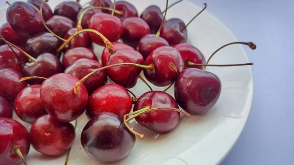 Red cherries on a plate, dark background. Ripe red berries close-up. Selective focus — Stock Photo, Image