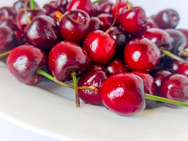  Beyaz arka planda kirazlar. Böğürtlenler beyaz tabakta. Seçici odak