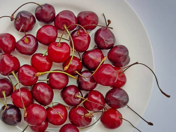 Red cherries on a plate, dark background. Ripe red berries close-up. Selective focus
