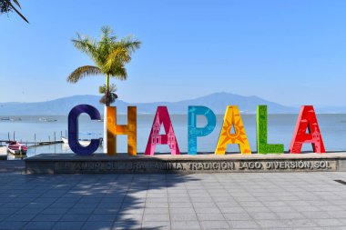 Colorful Chapala sign with painted letters and the lake in the background clipart
