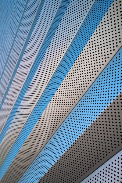 Çağdaş bir binada dış kaplama olarak kullanılan delikli metal levha modülleri. Yüksek teknoloji, minimalist, metropolitan ve grunge mimari tarzı. Yenileme malzemeleri.