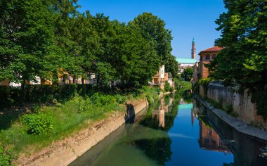 Vicenza şehrinden geçen Retrone nehri Palladian Bazilikası Piazza dei Signori boyunca akar ve Ponte San Michele 'in altından geçer. Büyük ağaçlar, berrak bir bahar günü, İtalya.