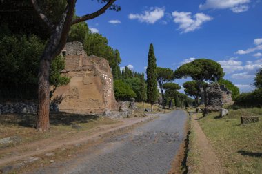 Güneşli bir günde Via Appia 'daki tuğla mezar fotoğrafı çekildi. Roma İmparatorluğu 'nun en önemli yollarından biriydi. Kalıntılar kaldırımlardan, diğer mezarlardan, zengin bitki örtülerinden, deniz çam ağaçlarından, selvilerden oluşuyordu..