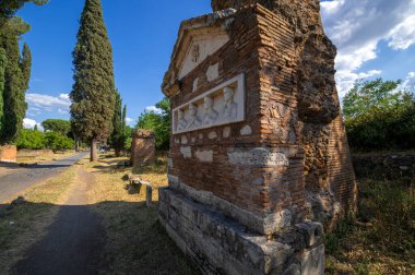 Güneşli bir günde Appia Antica 'nın fötr şapkası ve fötr şapka mezarı fotoğraflandı. Roma İmparatorluğu 'nun en önemli yollarından biriydi. Kaldırım kalıntıları, diğer mezarlar, zengin bitki örtüsü, deniz çamları ve selvi ağaçları..