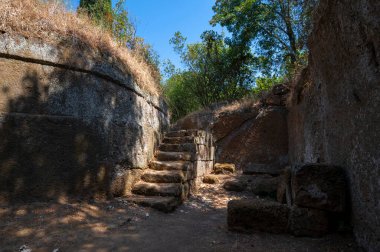 Etrüsk mezarlığı, Tuff Tumulus mezarı, güneşli bir yaz gününde mavi gökyüzü ile çekilmiş bir merdiven. Antik Etrüsk şehri, Banditaccia 'nın mezarlığı Tuff Hill' de. Cerveteri, İtalya.