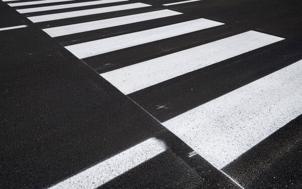 Side view of the pedestrian crossing, asphalt road, white stripes on a dark gray background, zebra stripes, perspective views, black and white, high temperature resistant draining asphalt.