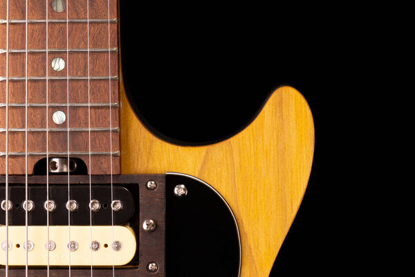 Front part of the body of an electric guitar on black background.