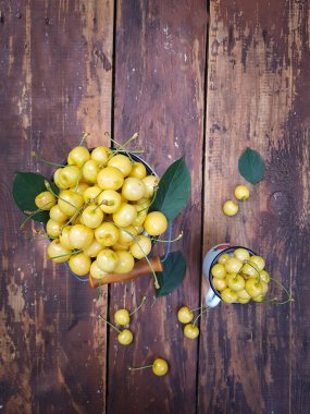 Dolu emaye konservesi ve ahşap bir masada bir kupa tatlı sarı kiraz.