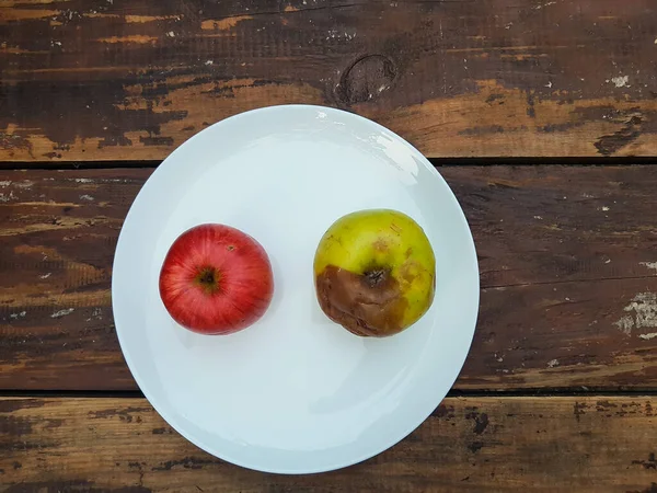 Άσχημο Κίτρινο Μήλο Και Κόκκινο Ώριμο Μήλο Λευκό Πιάτο Στο — Φωτογραφία Αρχείου