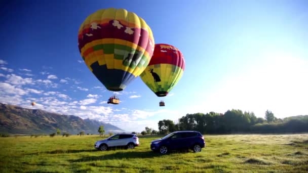 山の中で車の上を飛ぶ熱気球の風光明媚な映像 — ストック動画