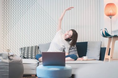 Genç Asyalı kadın oturma odasında yoga dersi alıyor.
