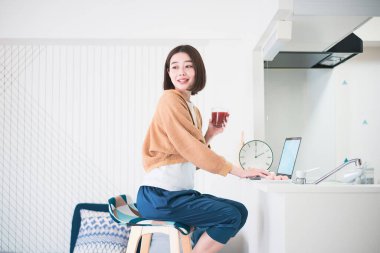 Evde dizüstü bilgisayarla uzaktan çalışan Asyalı genç bir kadın.