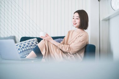 Asyalı genç bir kadın evdeki bilgisayar ekranına bakıyor.